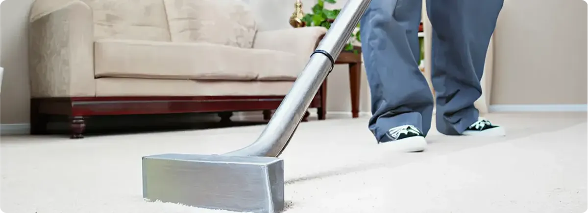 Carpet cleaning technician using a hot-water extraction wand on a light-colored carpet in a living room, Marietta, GA.