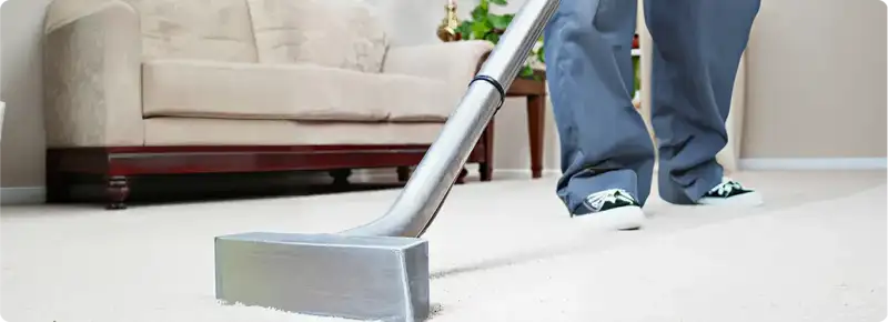 Carpet cleaning technician using a hot-water extraction wand on a light-colored carpet in a living room, Marietta, GA.