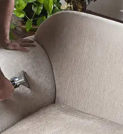 Professional upholstery cleaner deep-cleaning a fabric sofa with a handheld extraction tool and hose Marietta, GA.